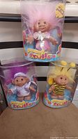 All three Troll dolls in packaging, stacked for scale and completeness