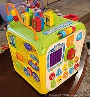 Three-quarter view of cube showing bead maze, gears, and side activities