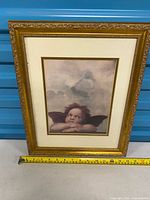 Full view of framed cherub print showing overall design and tape for scale