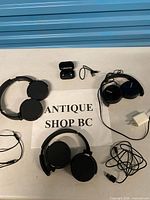 All items in lot: Maxell headphones, Sony headphones, Play Nice earbuds with case, USB cable, wall adapter