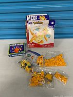 Front view: open Dragonite set box, instruction manual, sealed and zip bags of bricks, Brain Games 2022 calendar