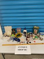 Overall lot on table showing gnome, ornaments, figurines, plush, boxes