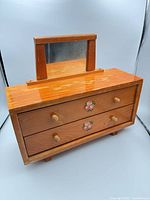 Front view showing drawers, knobs, floral decals, mirror, overall finish