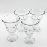 Four clear glass pedestal dessert cups grouped