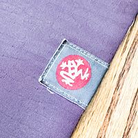 Close-up of Manduka label on purple mat surface
