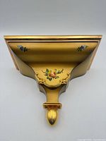 Front underside of shelf showing gold finish, floral painting and rococo scroll design