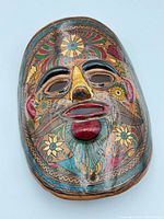 Front view of painted terracotta mask showing floral motifs and colors