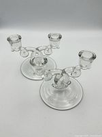 Both clear crystal double-arm candlesticks showing full shape and bases
