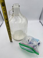 Full view of glass carboy with measuring tape and accessory bag