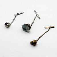 Front view of three tie tacks showing decorative heads and chains