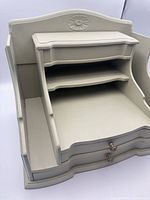 Front view showing drawers, shelves, carved motif