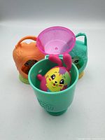 Front view of all three pods, pink lid removed to show interior of green pod