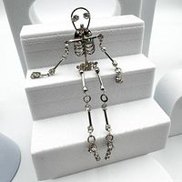 Full view of silver-tone articulated skeleton pin with rhinestone details