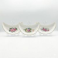 Front view of all three porcelain crescent dishes showing floral motifs and gold trim