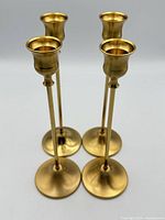 Full view of four gold-tone taper candle holders