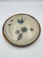 Top view of Tonalán hand-painted ceramic plate showing bird, flowers and rust-accented rim