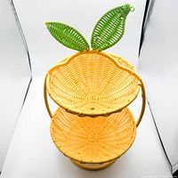 Front view of upright two-tier yellow wicker basket with green leaf accent