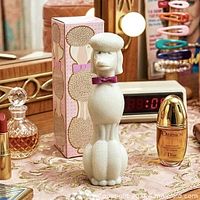 White glass poodle bath oil bottle with pink bow tie standing beside original pink patterned box