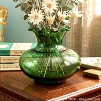 Green glass vase styled with flowers on table