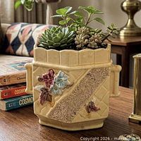Front view of yellow ceramic planter showing quilted texture, gold sand band, and applied flowers