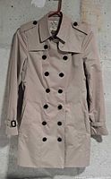 Front view of khaki Burberry trench coat on hanger
