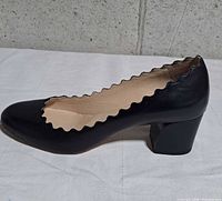 Left side profile of one pump showing scalloped edge and block heel