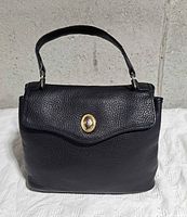 Front view of black leather Christian Dior flap handbag with gold-tone snap closure