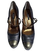 Top view of both pumps showing metallic gray leather, buckle straps, gold insoles, brand labels