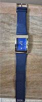 Full view of watch laid flat showing overall length and blue leather strap