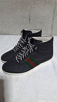 Side view showing black canvas upper, red and green stripe, and white sole