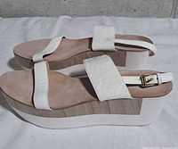 Side view showing off-white leather straps, wood midsole, white rubber platform