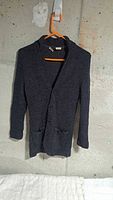 Front view of charcoal grey wool cardigan on hanger showing buttons and pockets