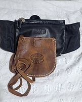 Front view: black Roots waist bag and brown Roots mini pouch