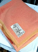 Folded salmon wool blanket with Eskimo brand label visible