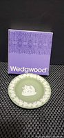 Front of sage green jasperware plate beside purple Wedgwood box