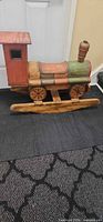 Left side view of wooden train rocker showing runners, cab, wheels and paint wear
