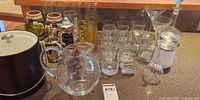 Overall lot view showing decanter, pitcher, rocks glasses, martini glasses, pilsner glasses, cordial glasses, steins, ice bucket