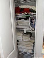 Full linen closet view showing stacked towels, tablecloths, pillowcases