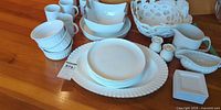 Entire lot laid out showing platter, plates, bowls, mugs, ramekins, basket bowl, creamer, gravy boat, shakers, small square plates
