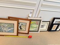 All framed artworks and empty frames lined up with tape measure for scale