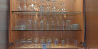 Overall cabinet view with two shelves of assorted clear glass drinkware