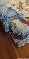 Stack showing plaid duvet cover, multicolor pillowcase, woven fringe blanket, beige blanket