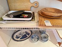 Shelf with cutting boards, trays, wicker plate, ceramic dish and spice shaker