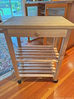 Full view of kitchen cart showing drawer, two slatted shelves, casters