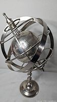 Full view of metal armillary sphere on pedestal stand