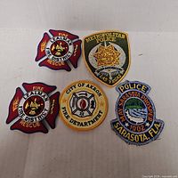 All five embroidered police and fire department patches displayed on flat surface