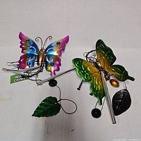 Both butterfly wind chimes displayed flat showing colors, tubes, leaf windcatchers