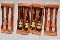 Four boxed pairs of Halloween taper candles, two white ghost design, two black pumpkin design