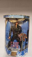 Front view of boxed Elvis Presley doll showing figure, guitar and mic