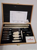 Overall view of open Winchester cleaning kit showing all components in wooden case